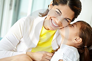 Giving mom a loving kiss. A cute young girl kissing her pretty mother on the cheek.