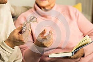 Giving senior woman reading glasses