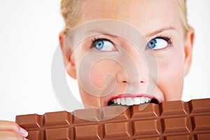 Giving in to her cravings. Crazed young woman biting into a huge piece of chocolate.