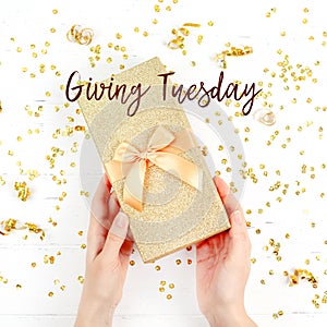 Giving Tuesday concept with golden box in hands