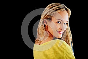 Giving you a coy smile. Studio portrait of a beautiful young blonde woman looking over her shoulder isolated on black.