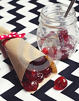 Glace cherries in paper cone on chevron background