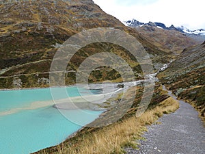 Lakeside hiking trail at glacial stream inflow in alpine landscape