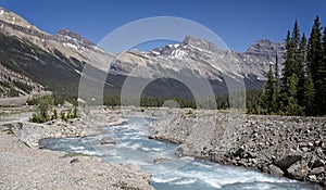 Glacial white water river with snow capped mountains in the background in Banff National Park in the Canada