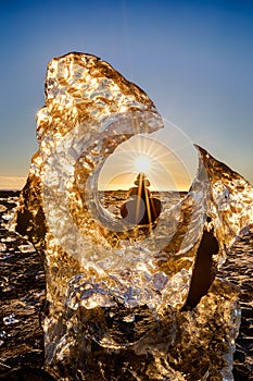 Glacier and balanced rocks with sun star on Iceland`s Diamond Beach with black sand