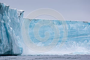 A glacier, carving, with floating sea ice north of Svalbard in the Arctic, with water falls