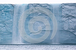 A glacier with floating sea ice north of Svalbard in the Arctic, with water falls