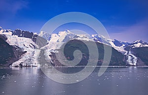 The glacier flows into the lake, which has bits of ice on the surface.