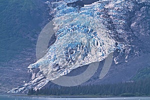 The glacier flows into the lake, which has bits of ice on the surface.