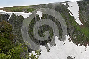 Glacier on mountain stone slope. Snow covers rocks, making it difficult to climb to top. Cliffs in ice