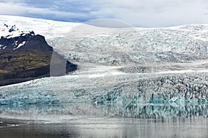 The glacier is reflected in the water of the lake. Beautiful northern landscape. Iceland. Ecological problems of melting glaciers.