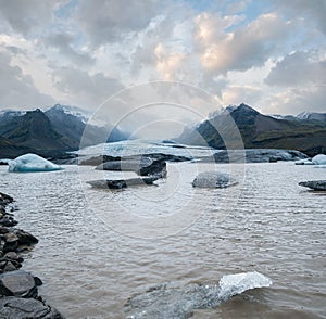 Glacier tongue slides from Vatnajokull icecap or Vatna Glacier near subglacial Oraefajokull volcano, Iceland. Glacial lagoon with