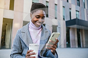Glad African American woman browsing mobile phone