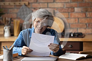 Glad aged latin lady read paper letter with good news