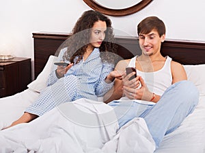 Glad boyfriend and girlfriend busy with smartphones
