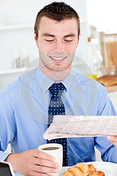 Glad businessman reading newspaper drinking coffee