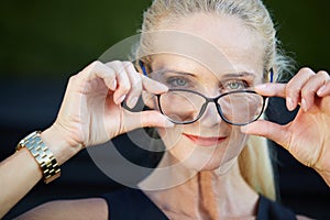 Glad businesswoman holding spectacles