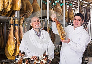 Glad butchery technologists checking joints of iberico jamon