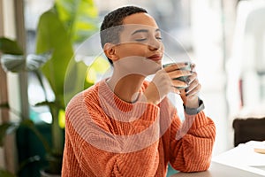 Glad calm pretty young latin woman enjoy peace and spare time, drink cup of coffee, warm moment