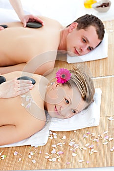 Glad couple receiving back massage with hot stones