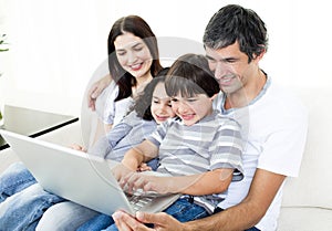 Glad family using a laptop sitting on sofa