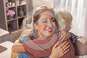 Glad female hugging granny in apartment