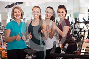 Glad females of different age training on exercise bikes