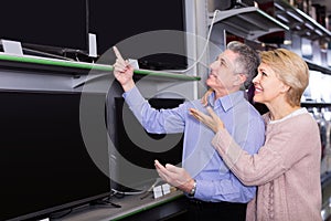 glad husband and wife choose for themselves TV in center of electronics photo
