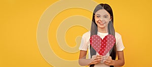 glad kid hold love heart on yellow background, valentine day. Kid girl portrait with heart love symbol, horizontal