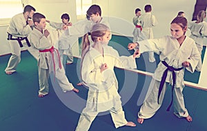 Glad kids sparring in pairs in karate class