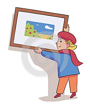 Glad little boy artist hanging picture on wall