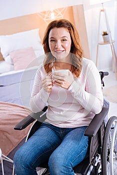 Glad lovely disabled woman holding a cup