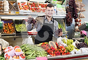 Glad male seller showing assortment of grocery shop