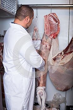 Glad male shop staff cutting sirloin at top