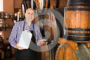 Glad male wine maker taking wine from wood