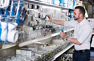 Glad man picking electric plug in household shop