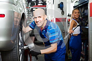 Glad man technician assembling new tires to car