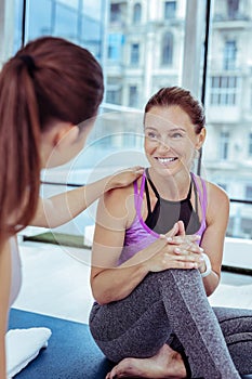 Glad mature woman prattling with yoga trainer