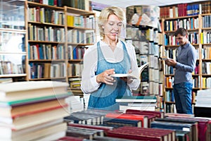 Glad mature woman reading book in book shop