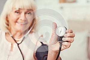 Glad old lady using tonometer at home
