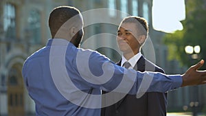 Glad parent hugging young son in suit outdoors university, prom celebration