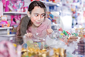 Glad schoolgirl delighted with choosing lollipop in store