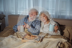 Glad senior couple having meal in bedroom