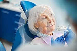 Glad senior female receiving a suggestion of silicone dental impression