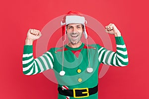glad shouting man in elf costume. xmas guy in santa claus hat on red background.
