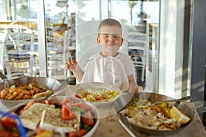 Glad small child eats sea seafood in a restaurant. Mediterranean diet. Healthy food for kids