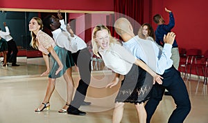 Glad smiling people practicing lindy hop technique in dance class