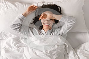 Glad smiling young european woman sleeping on white bed, waking up, enjoying vacation, good morning