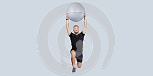 Glad strong muscular millennial european guy with beard, make exercises with fit ball for hands, enjoy workout