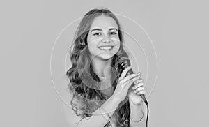 glad teen kid with microphone on yellow background